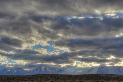 Scattered cumulus clouds hang above the Owens Valley as crepuscular rays beam down onto Mt. Tom and Wheeler Crest, CA