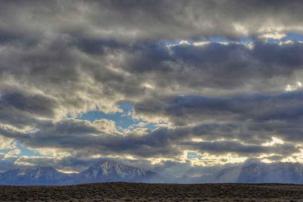 Scattered cumulus clouds hang above the Owens Valley as crepuscular rays beam down onto Mt. Tom and Wheeler Crest, CA