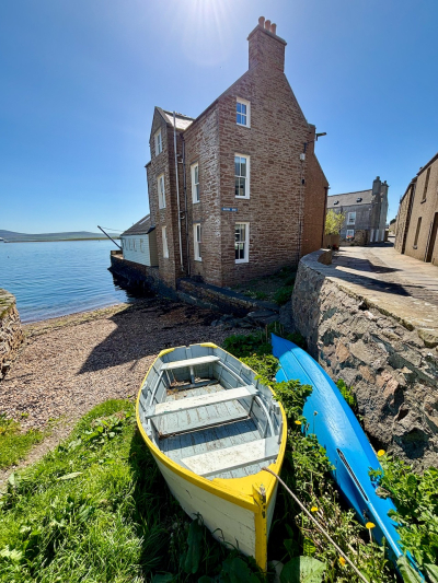 Waterfront home of local stone on a rare, calm and sunny day, Stromness.